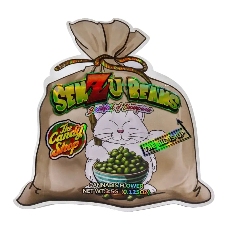 A die-cut sticker or decal shaped like a brown paper sack filled with green cannabis flower. The front features a cartoon white cat holding a bowl of green beans/peas, large stylized text reading 'SENZU BEANS,' smaller text including 'The Candy Shop,' and 'FIRE NINJA UP.